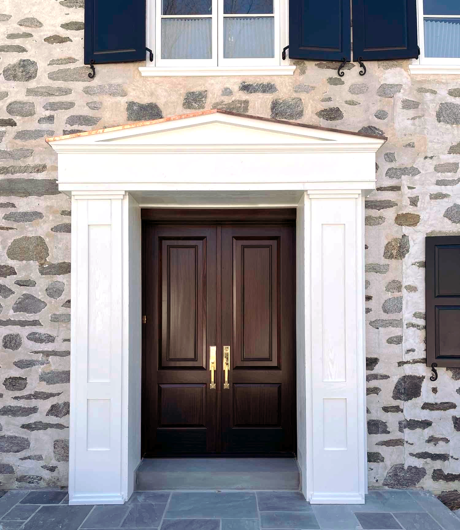 wooden front with glass panes and metal hardware surrounded by architectural stone